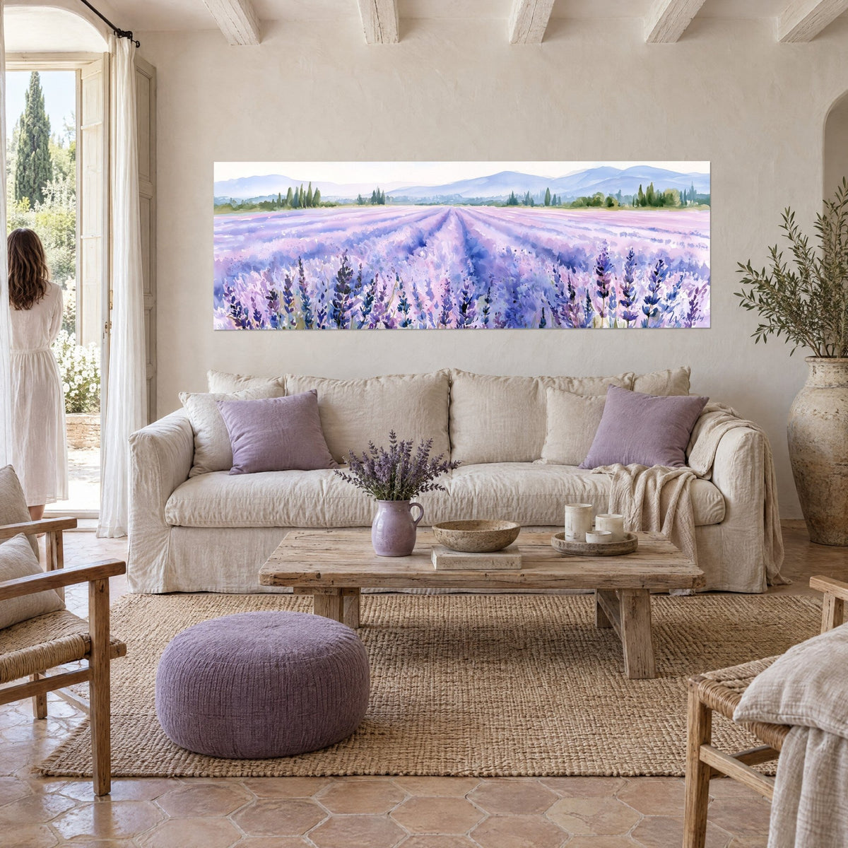 Cuadro campo de lavanda en acuarela, surcos morados y rosa pálido hacia colinas azuladas, sobre un sofá en un salón luminoso