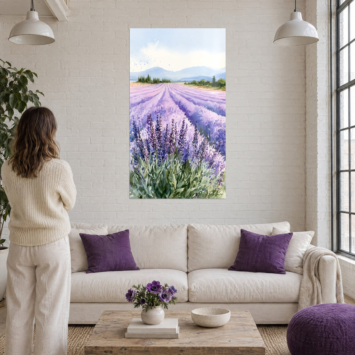 Wall art watercolor lavender field, lilac and blue rows rolling toward hills, woman seen from behind above a sofa in a bright living room