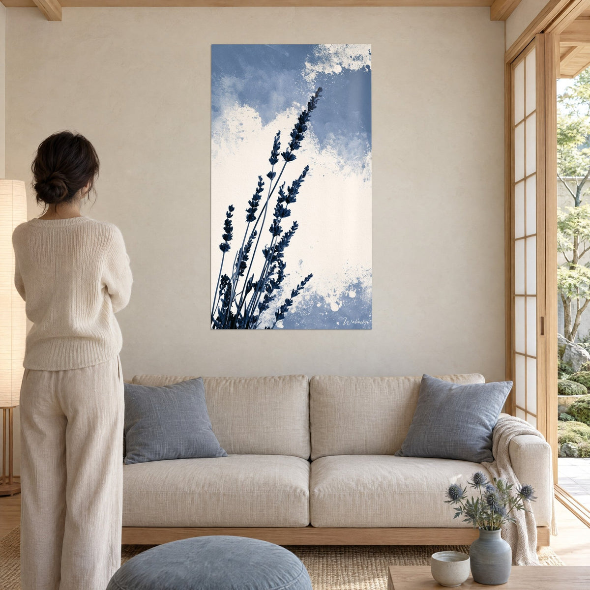 Gemälde mit dunkelblauen Lavendelähren auf cremefarbenen, gesprenkelten Wolken, Frau von hinten über einem Sofa in einem hellen Wohnzimmer