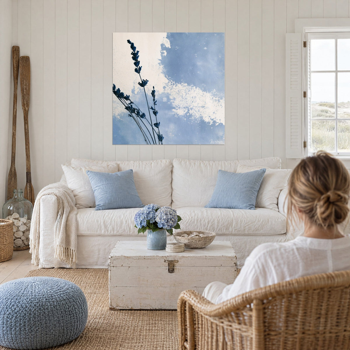 Cuadro lavanda seca con espigas azul marino sobre fondo azul cielo y blanco salpicado, encima de un sofá en un salón luminoso