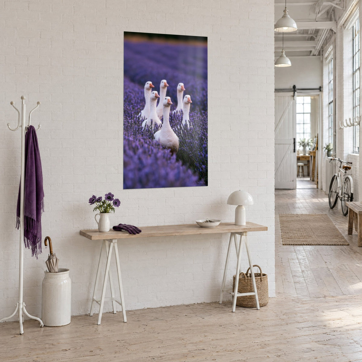 Wall art flock of ivory geese walking through a field of purple lavender, hung at an angle in an artist's loft