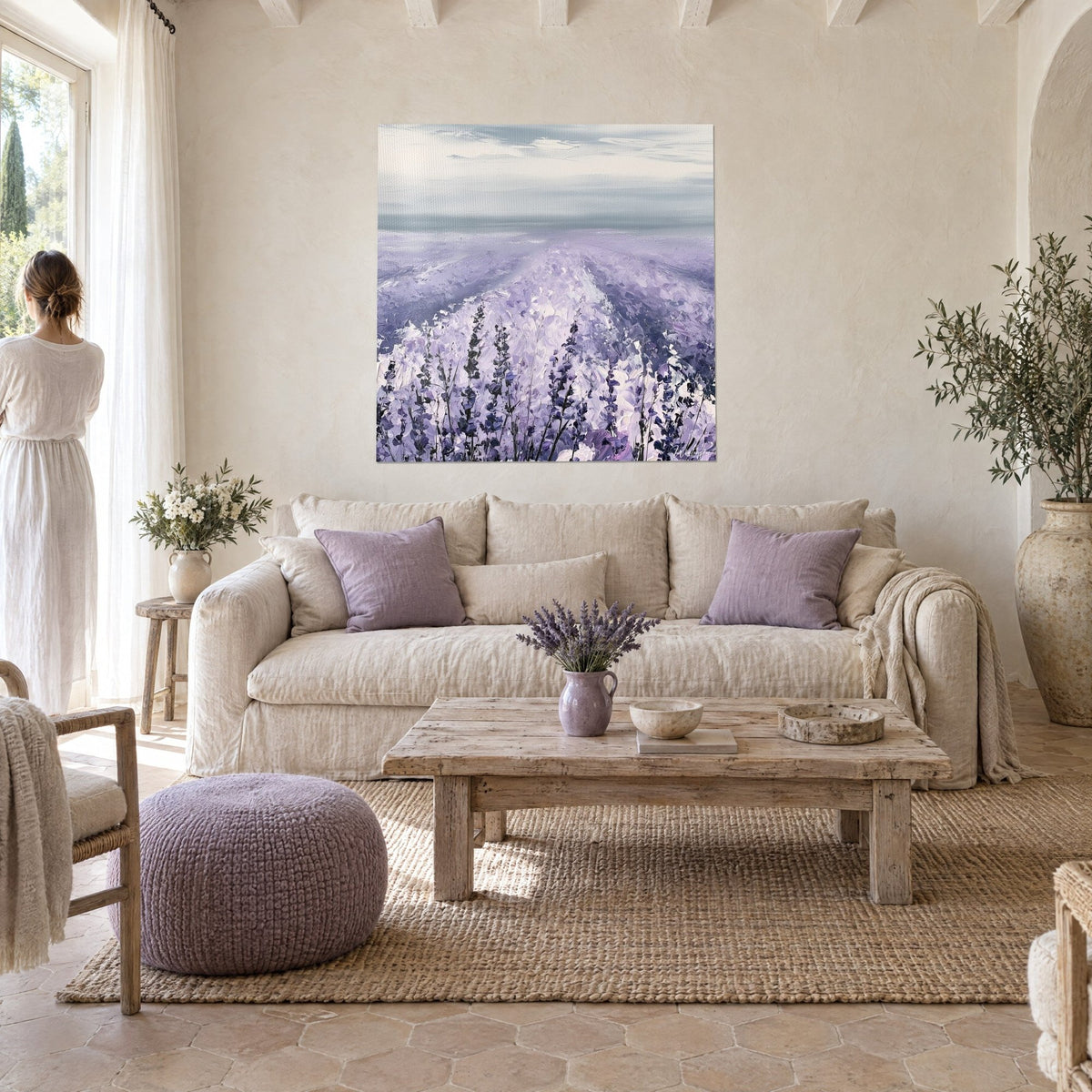 Cuadro campo de lavanda con espigas violetas bajo un cielo gris perla, mujer de espaldas, encima de un sofá en un salón luminoso