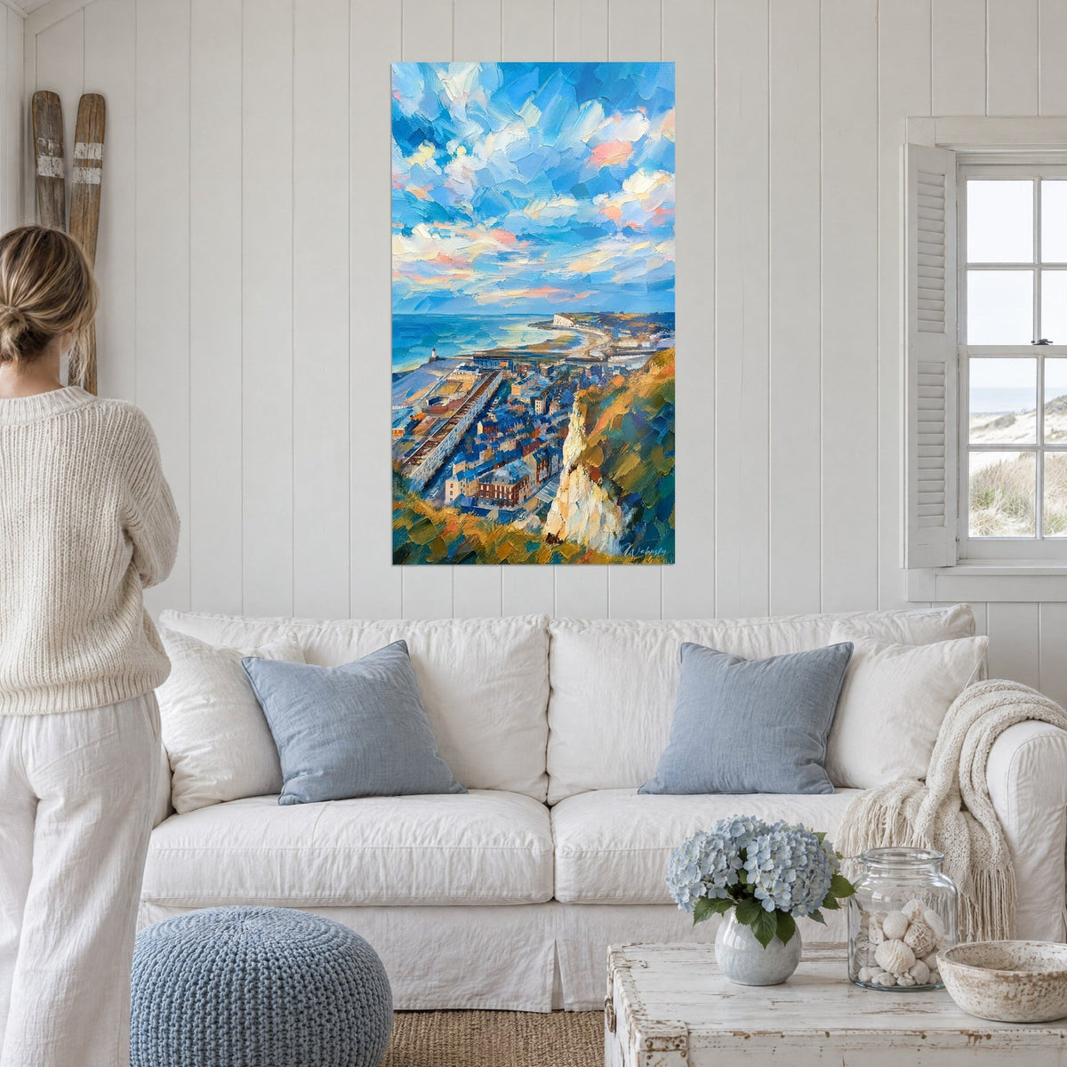 Quadro scogliere di gesso che dominano tetti azzurrati, cielo cobalto e toni rosa tenue, sopra un divano in un soggiorno luminoso