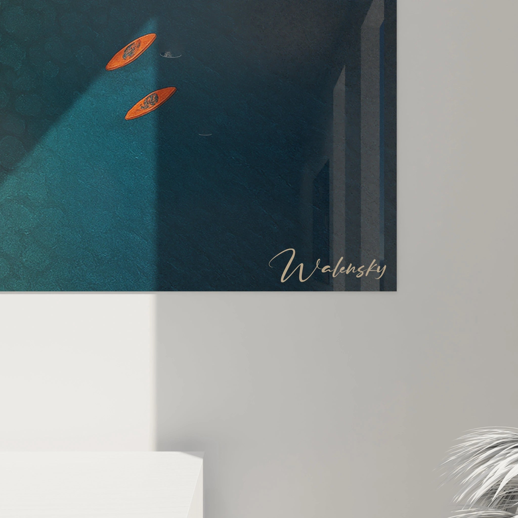 Un tableau vue aérienne présentant un rivage composé de pavés beiges et dorés qui se transforment graduellement en eaux bleues profondes, avec deux kayaks orange comme accent coloré sur la surface marine texturée.
