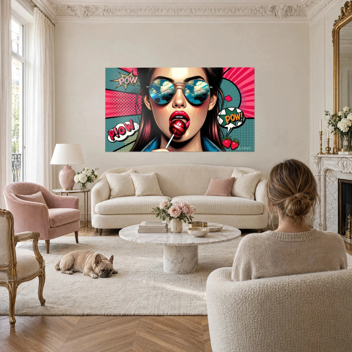 Wall art pop art print of a carmine mouth on a red lollipop, blue mirrored sunglasses, pink and turquoise background, above a sofa in a bright living room