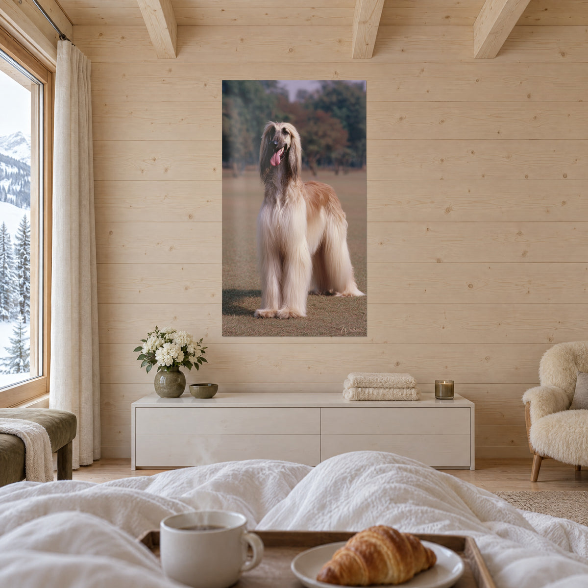 Quadro ritratto di cane slanciato, pelo sabbia e oro, lingua rosa, fogliame verde e ramato sfocato, sopra un letto in una camera luminosa