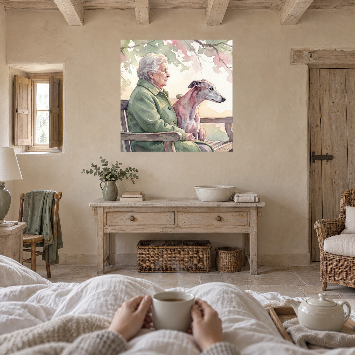 Schilderij van een grootmoeder in een olijfgroene jas die haar grijsroze windhond aait, roze en crèmekleurige bloemen, boven een bed in een lichte slaapkamer