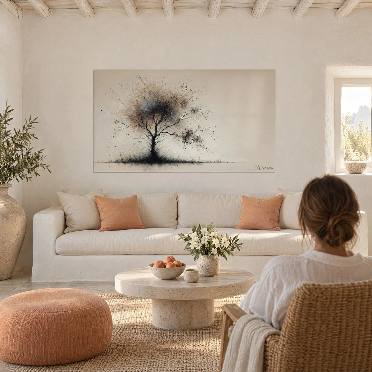 Tableau arbre de vie en encre noire, ramure poudrée de rose et de gris sur fond sable, au-dessus d'un canapé dans un salon lumineux