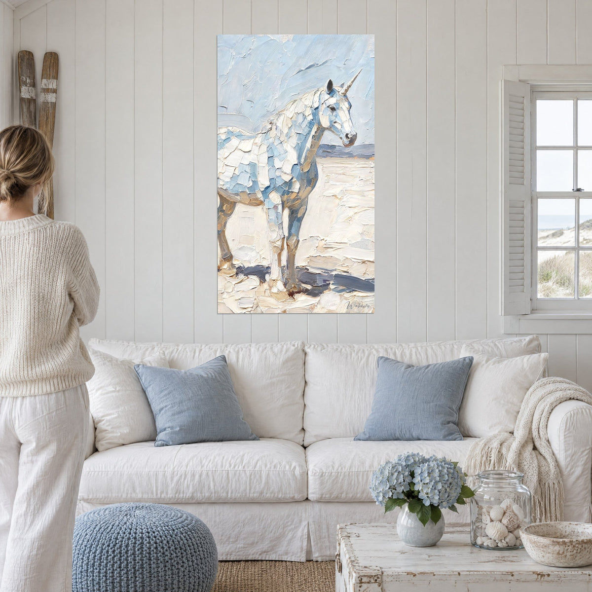 Wall art white unicorn with a pearly horn, pastel blue and cream gown in thick impasto, above a sofa in a bright living room
