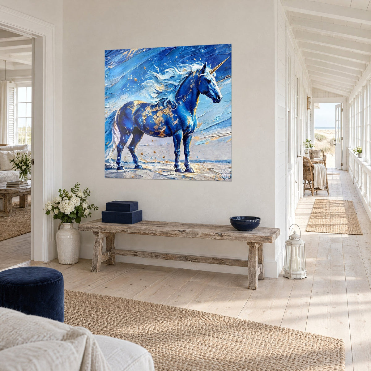 Wall art unicorn with golden horn, royal blue coat speckled with gold on a sky-blue background, hung above a wooden console in a seaside hallway