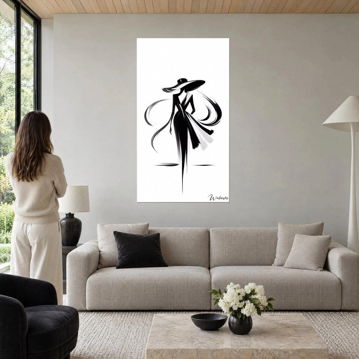 Tableau silhouette féminine au chapeau large, encre noire sur fond blanc, rubans en volutes, au-dessus d'un canapé dans un salon lumineux