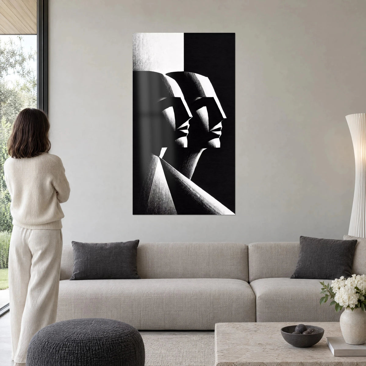 Tableau deux profils géométriques noir et blanc, arêtes taillées en facettes, femme de dos, au-dessus d'un canapé dans un salon lumineux