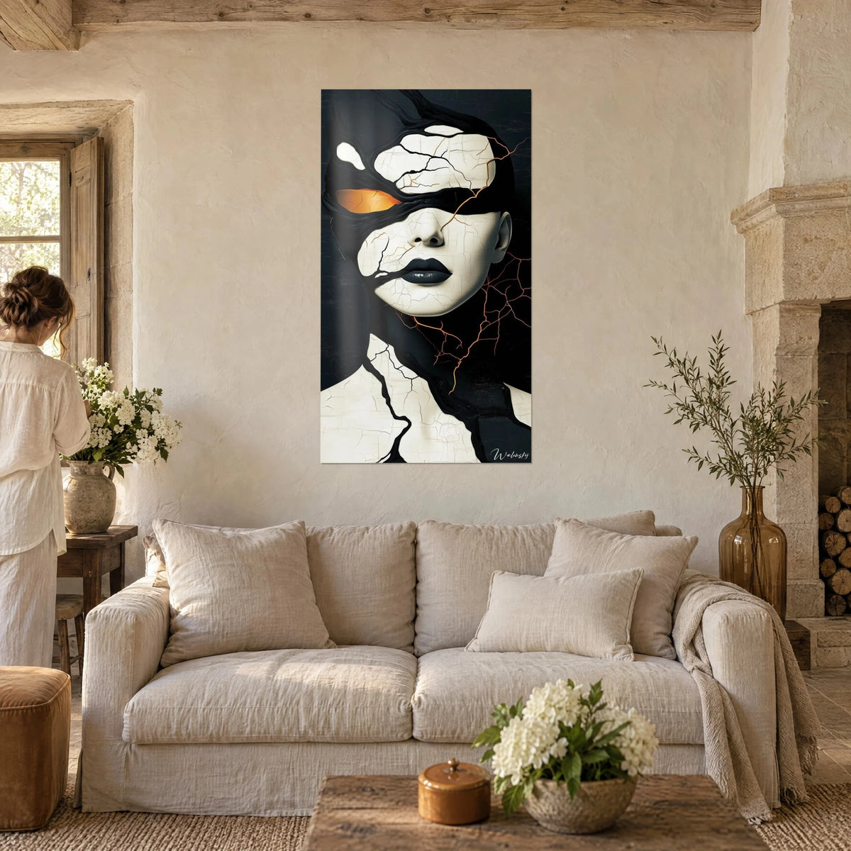 Wall art of a cracked woman's face, ivory skin and black lips, amber eye, above a sofa in a bright living room