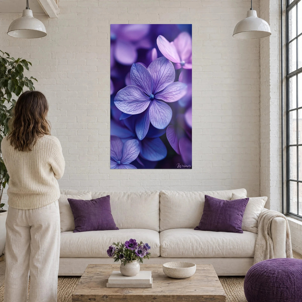 Cuadro hortensia violeta de nervaduras finas y corazón turquesa, cojines color ciruela, sobre un sofá en un salón luminoso