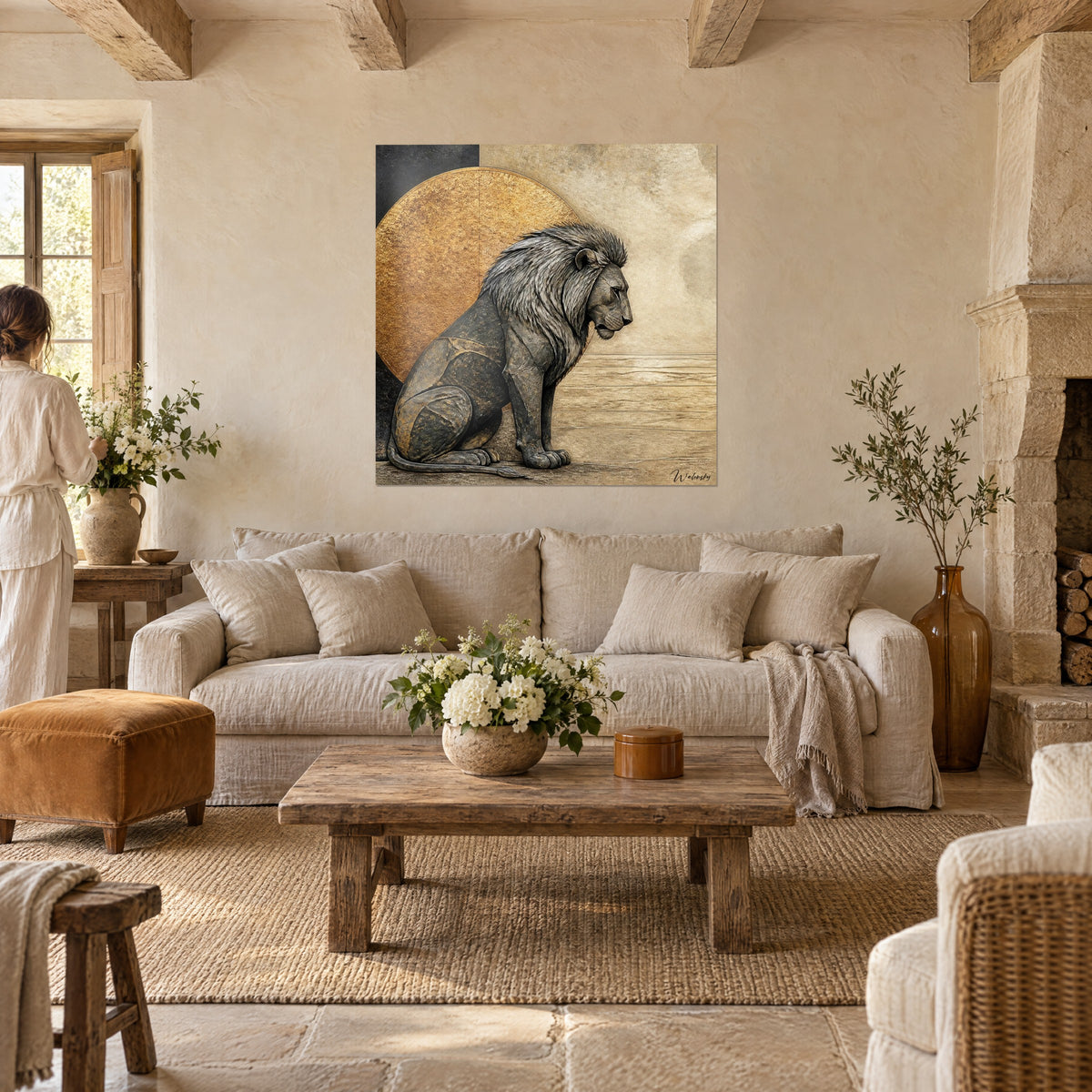 Tableau lion de pierre anthracite assis devant un disque or martelé, fond sable, deux personnes de dos, au-dessus d'un canapé dans un salon lumineux