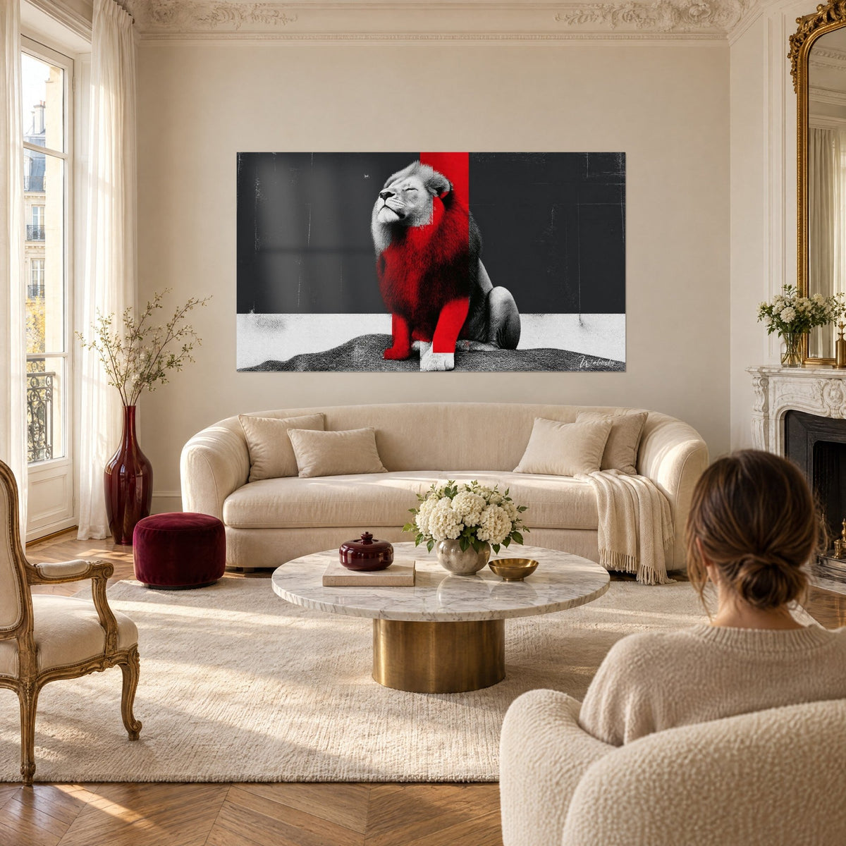Tableau lion assis, crinière rouge vif sur fond noir et blanc, deux personnes de dos, au-dessus d'un canapé dans un salon lumineux