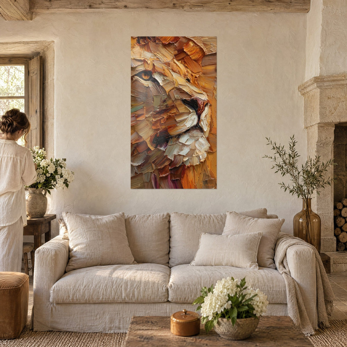 Wall art lion with a mane sculpted in ochre and ivory palette-knife strokes, woman seen from behind, above a sofa in a bright living room
