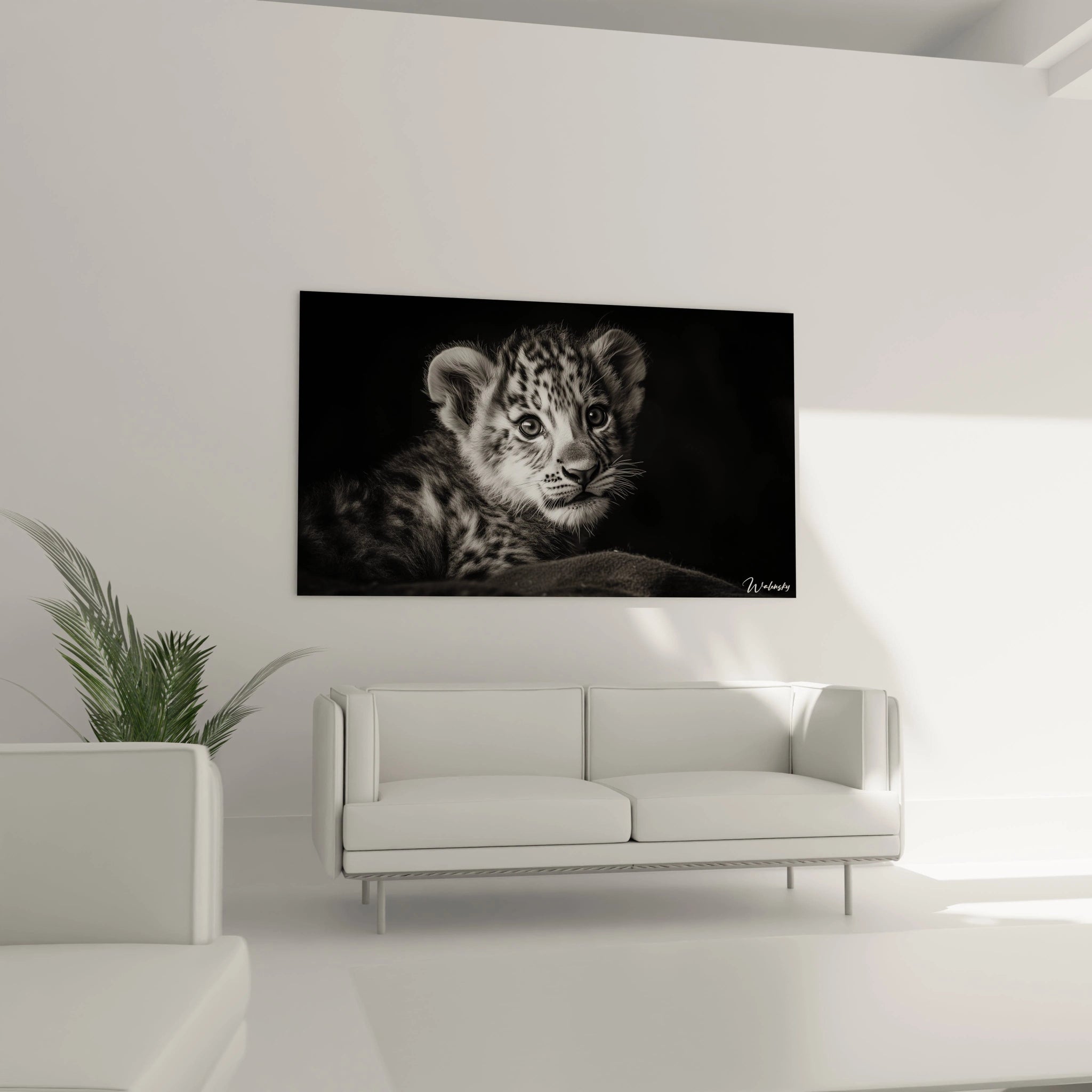Un tableau lionceau aux tons noir et blanc montrant un jeune félin avec des yeux brillants et attentifs, des oreilles arrondies et une fourrure tachetée finement détaillée, créant un contraste saisissant avec l'arrière-plan noir profond.
