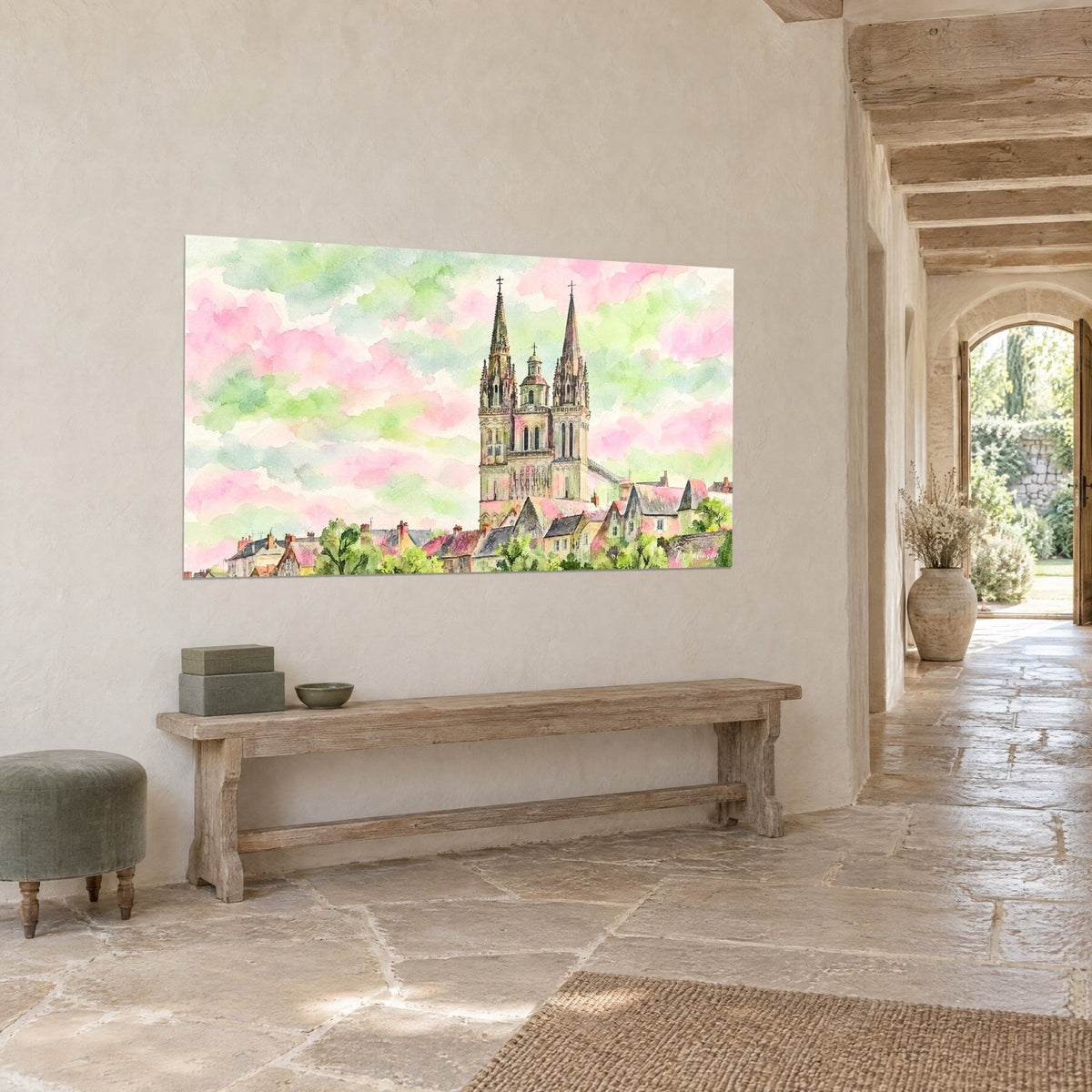 Cuadro campanarios gemelos de piedra gris sobre nubes rosa pálido y verde anís, colgado frente a un banco de madera, losas claras