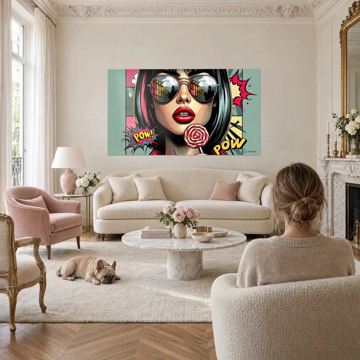 Cuadro pop art de una mujer con cuadrado negro y rosa, labios rojos, piruleta en espiral, verde agua, sobre un sofá en un salón luminoso