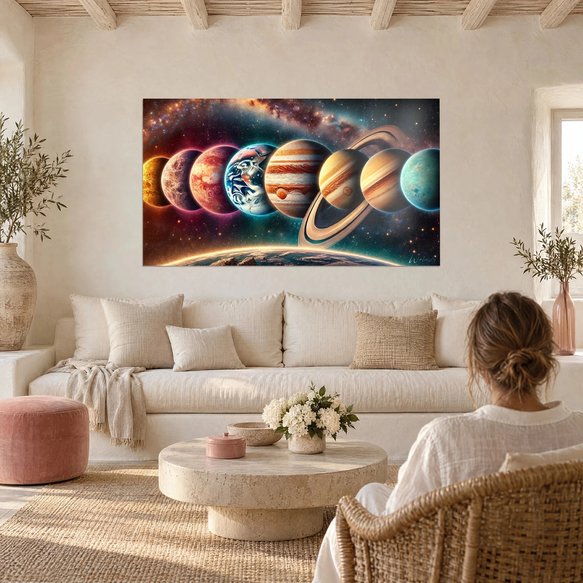 Wall art aligned planets against a Milky Way backdrop, orange Jupiter and blue Earth, couple seen from behind above a sofa in a bright living room