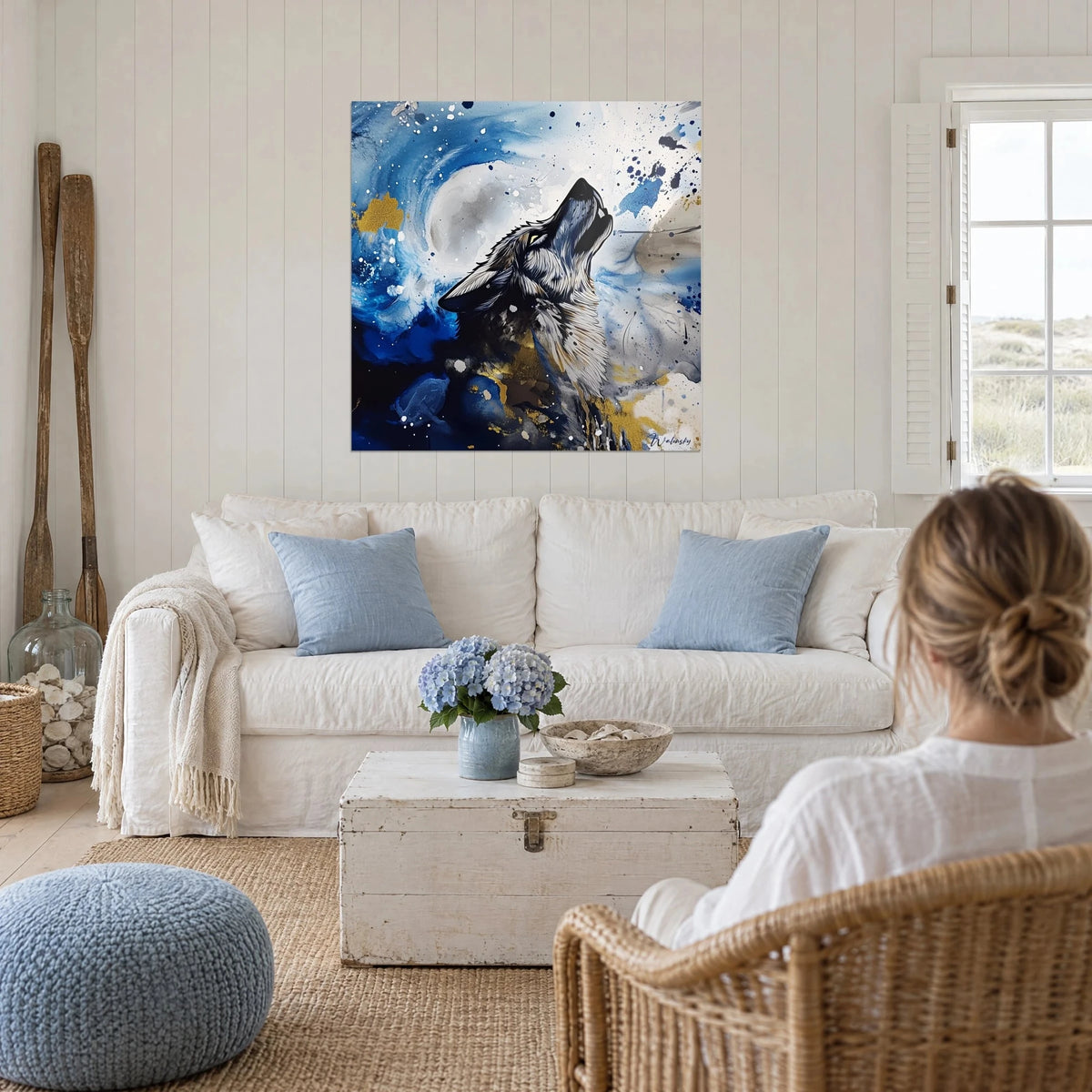 Tableau loup hurlant vers la lune, bleu cobalt et éclats d'or, personne de dos, au-dessus d'un canapé dans un salon lumineux