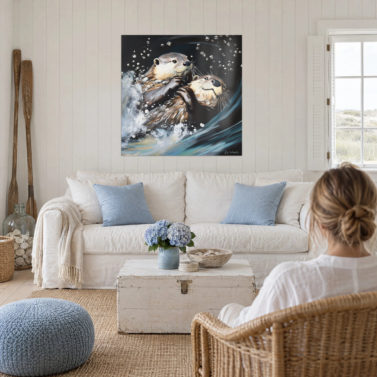 Tableau deux loutres brunes enlacées dans les remous bleu nuit, bulles d'argent, au-dessus d'un canapé dans un salon lumineux