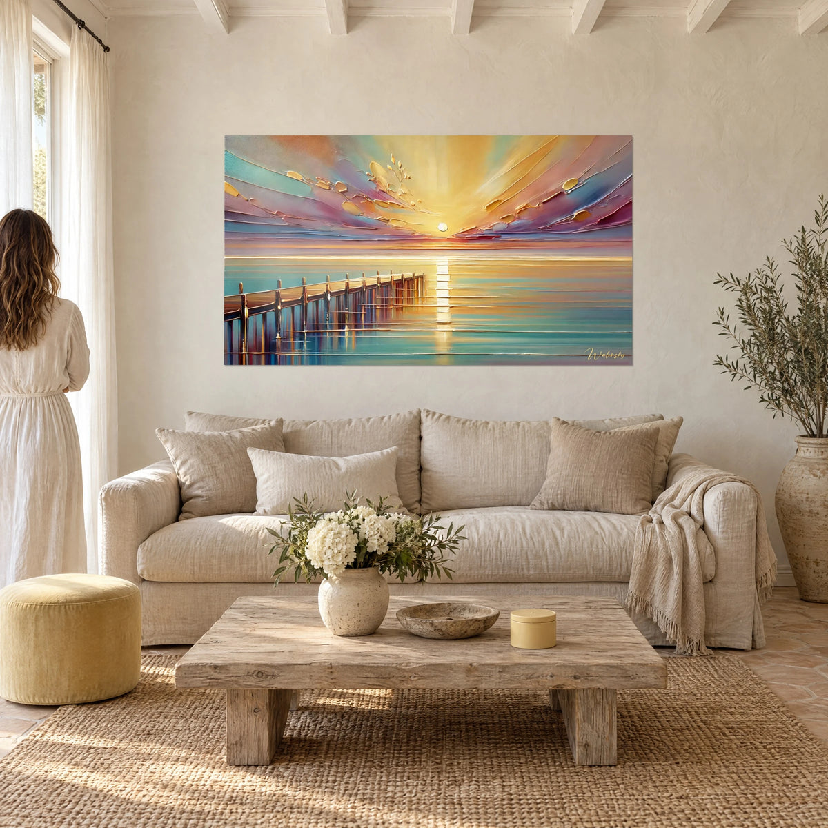 Tableau soleil couchant sur la mer, ciel doré et rose, ponton brun ; femme de dos, au-dessus d'un canapé dans un salon lumineux