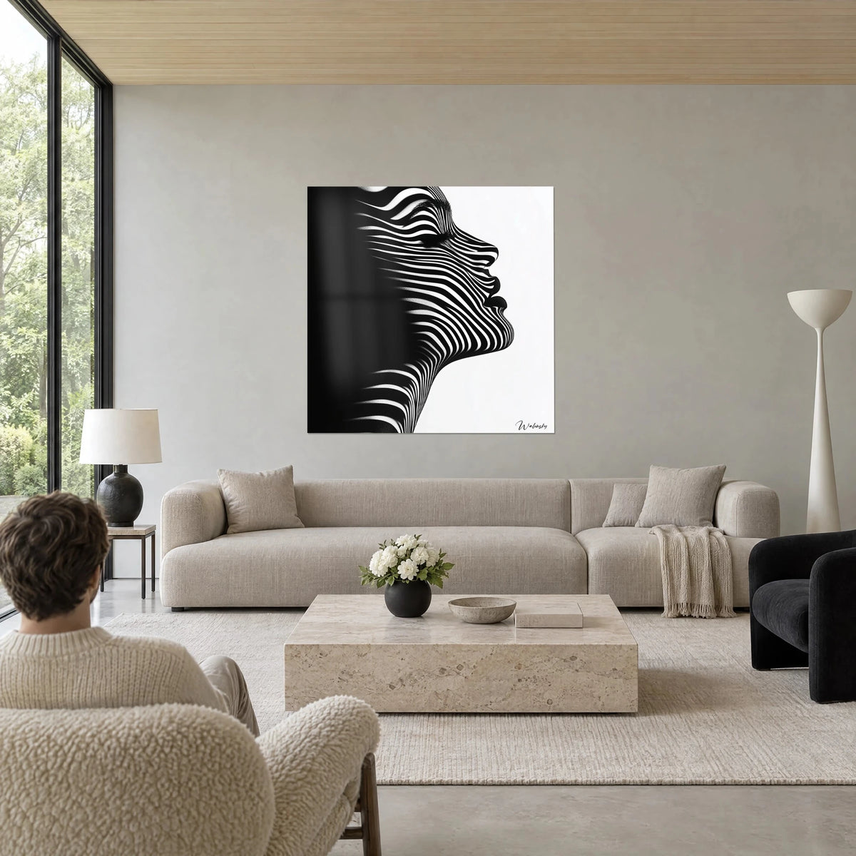 Wall art female profile in black and white zebra stripes, raised forehead, one side plunged in shadow, above a sofa in a bright living room