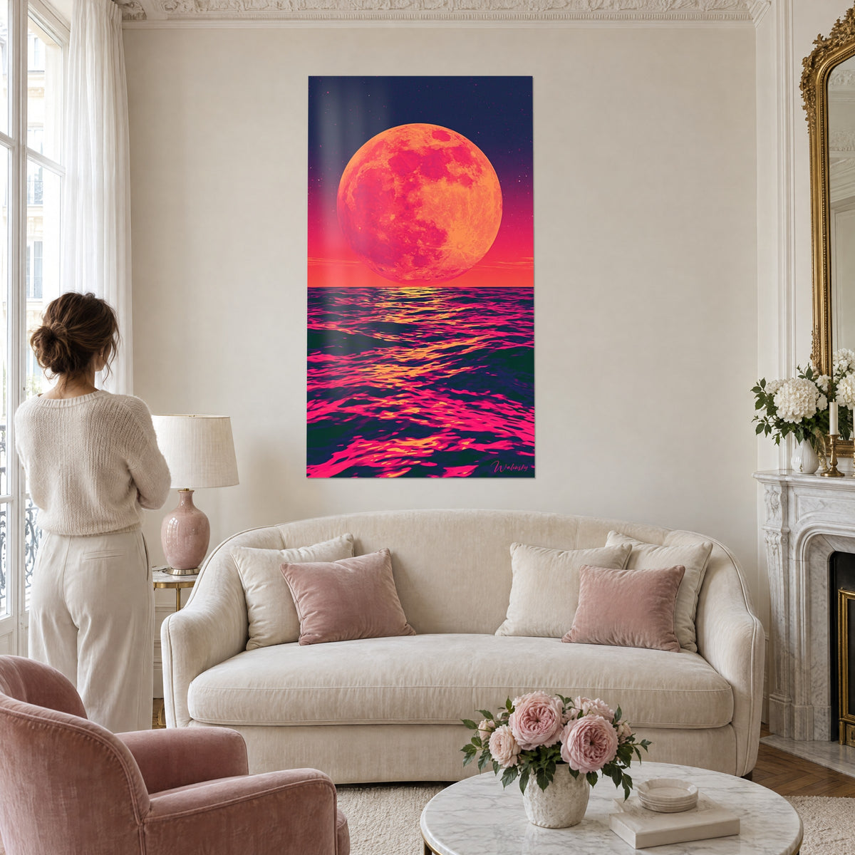 Wall art orange cratered full moon over magenta and indigo sea, a woman seen from behind above a sofa in a bright living room