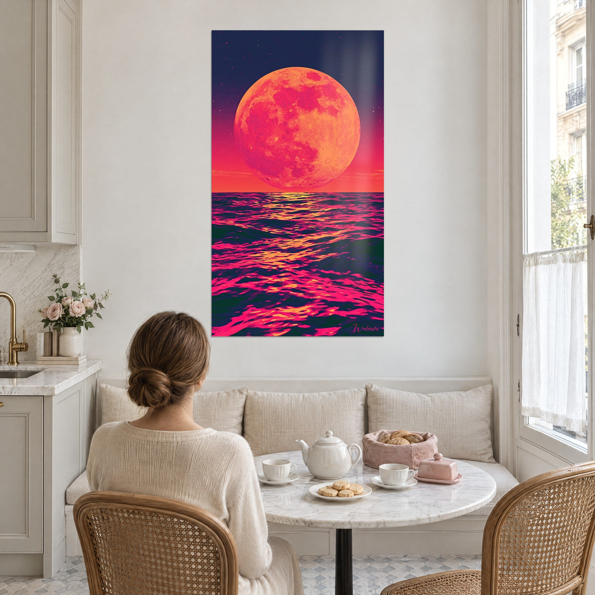 Wall art apricot lunar disc dominating a magenta and dark green ocean, a woman seen from behind having tea in a kitchen