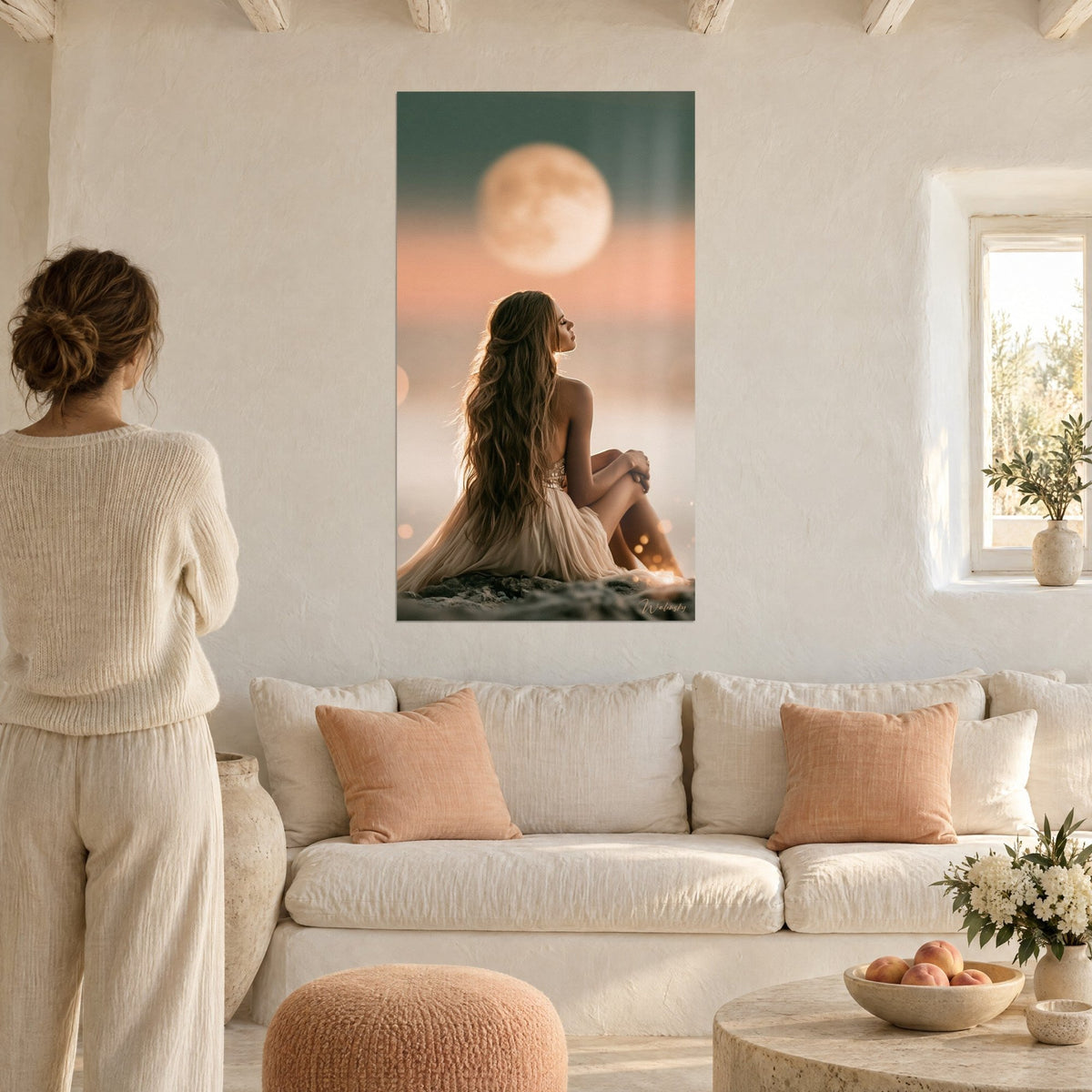 Tableau jeune femme aux longs cheveux châtains face à une pleine lune dorée, ciel sauge et pêche, au-dessus d'un canapé dans un salon lumineux