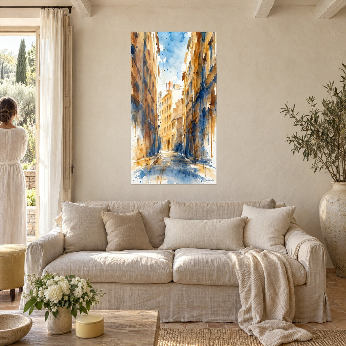 Wall art of a Lyon alleyway with ochre and cobalt blue facades, watercolour drips, above a sofa in a bright living room