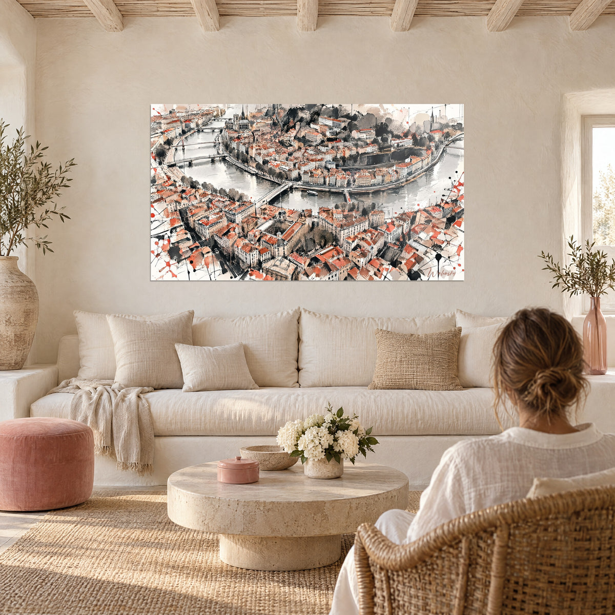 Wall art aerial view of Lyon with terracotta rooftops and grey rivers, woman from behind, above a sofa in a bright living room