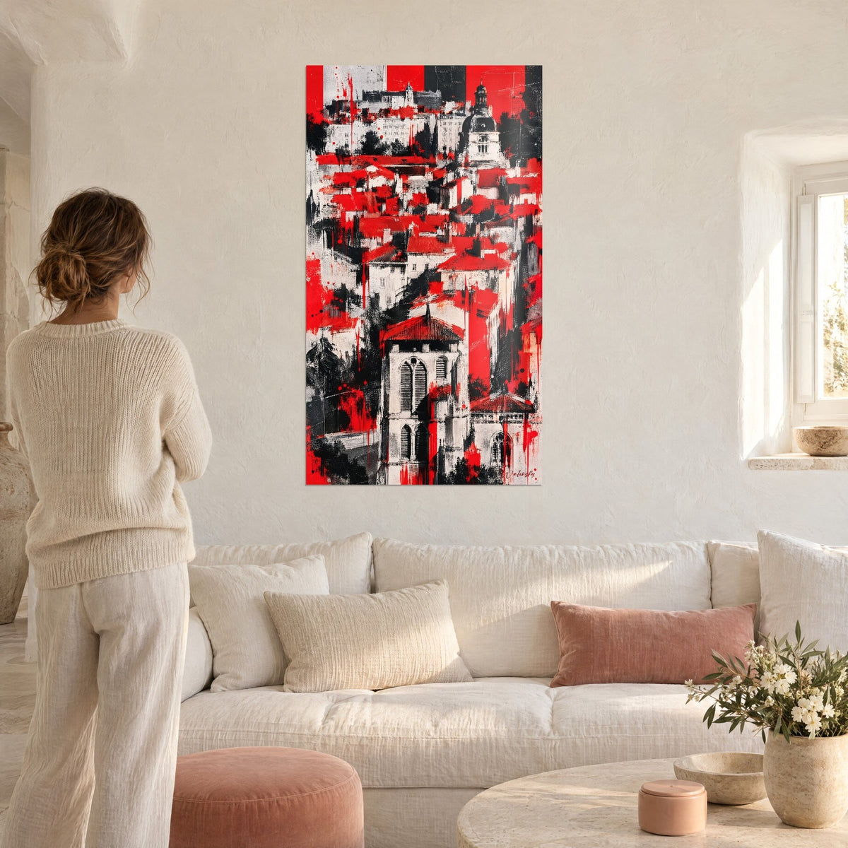 Wall art red and black gothic bell tower on a splattered hill, scarlet rooftops, woman seen from behind, above a sofa in a bright living room