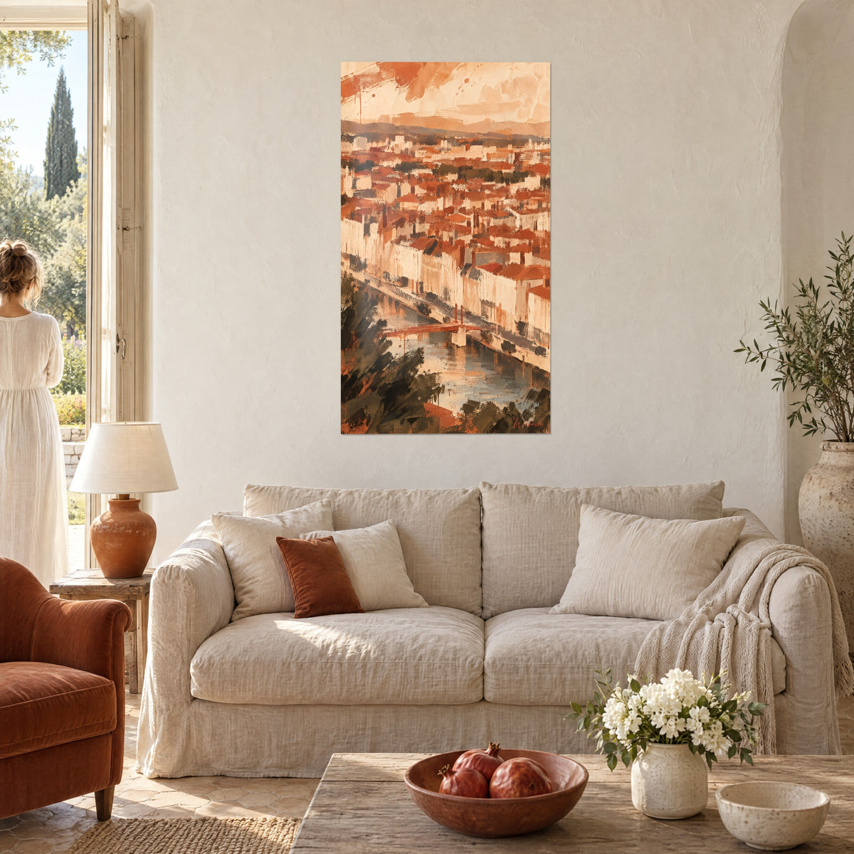 Wall art panoramic view of terracotta rooftops and ochre facades along a river, woman seen from behind, above a sofa in a bright living room