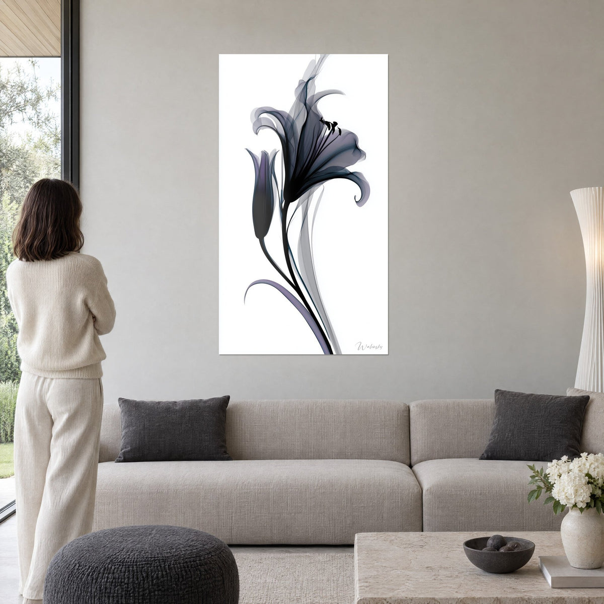 Quadro giglio nero traslucido dai petali grigio-viola, calice e boccio su sfondo bianco, sopra un divano in un soggiorno luminoso