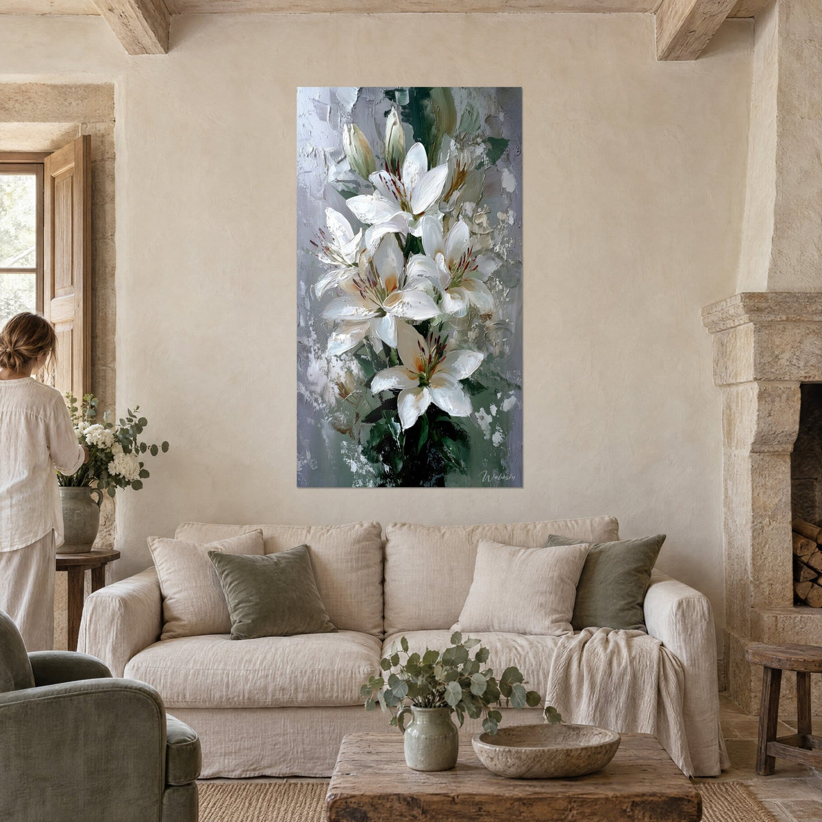 Tableau lys blancs en bouquet, étamines brun rouille sur fond gris-vert, une femme de dos, au-dessus d'un canapé dans un salon lumineux