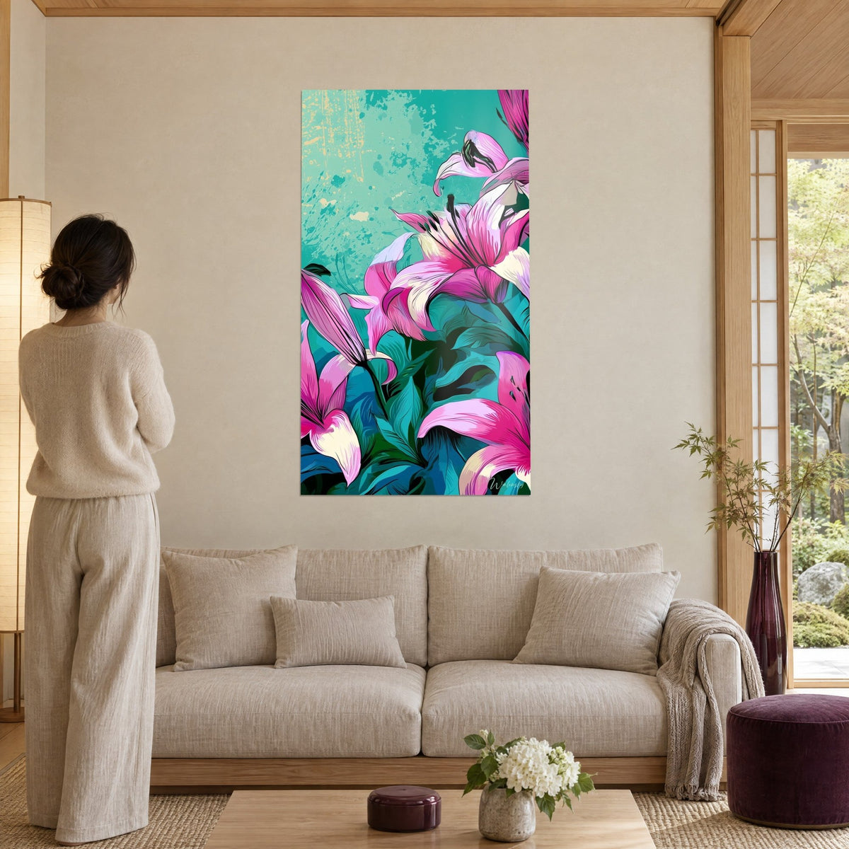Tableau lys roses aux pétales fuchsia et crème sur fond turquoise, femme de dos, au-dessus d'un canapé dans un salon lumineux