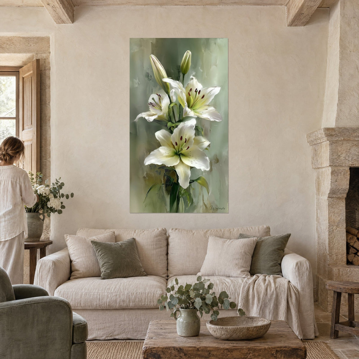 Tableau lys blanc à la gorge verte, étamines bordeaux, fond sauge peint, personne de dos, au-dessus d'un canapé dans un salon lumineux