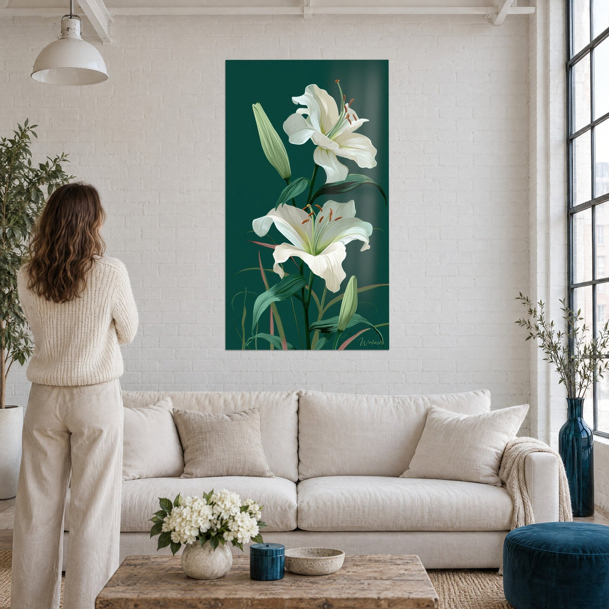 Tableau lys blanc aux pétales ondulés sur fond vert émeraude, étamines orangées, au-dessus d'un canapé dans un salon lumineux