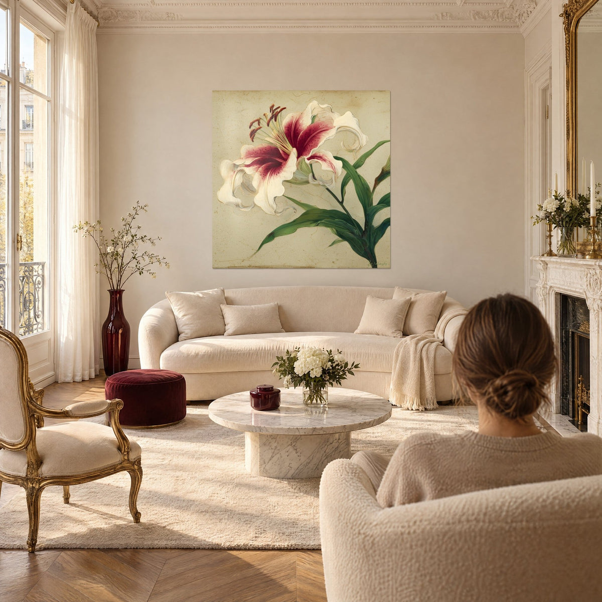 Tableau lys rose et crème aux étamines cuivrées, feuilles vert sapin, au-dessus d'un canapé dans un salon lumineux