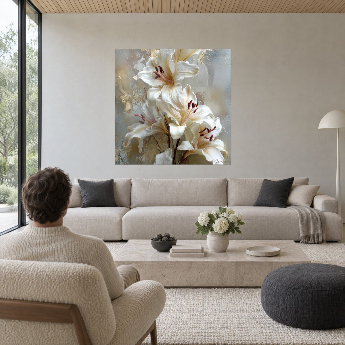 Tableau grands lys blancs aux étamines pourpres sur fond gris doré, homme de dos, au-dessus d'un canapé dans un salon lumineux