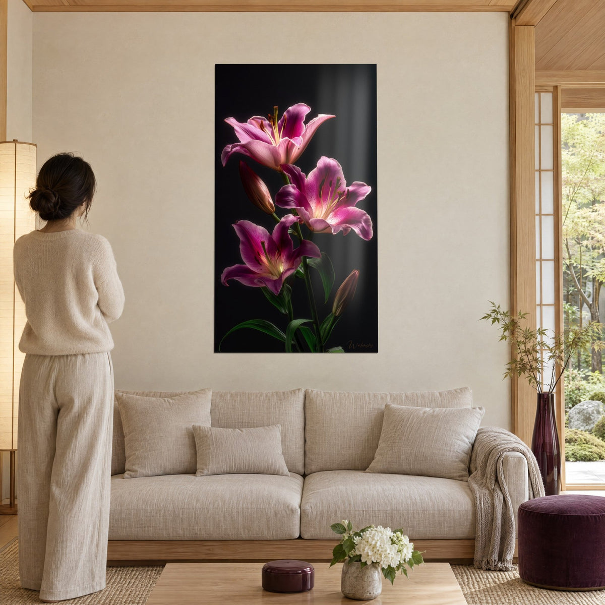 Tableau lys magenta aux étamines dorées sur fond noir, femme de dos, canapé beige, au-dessus d'un canapé dans un salon lumineux