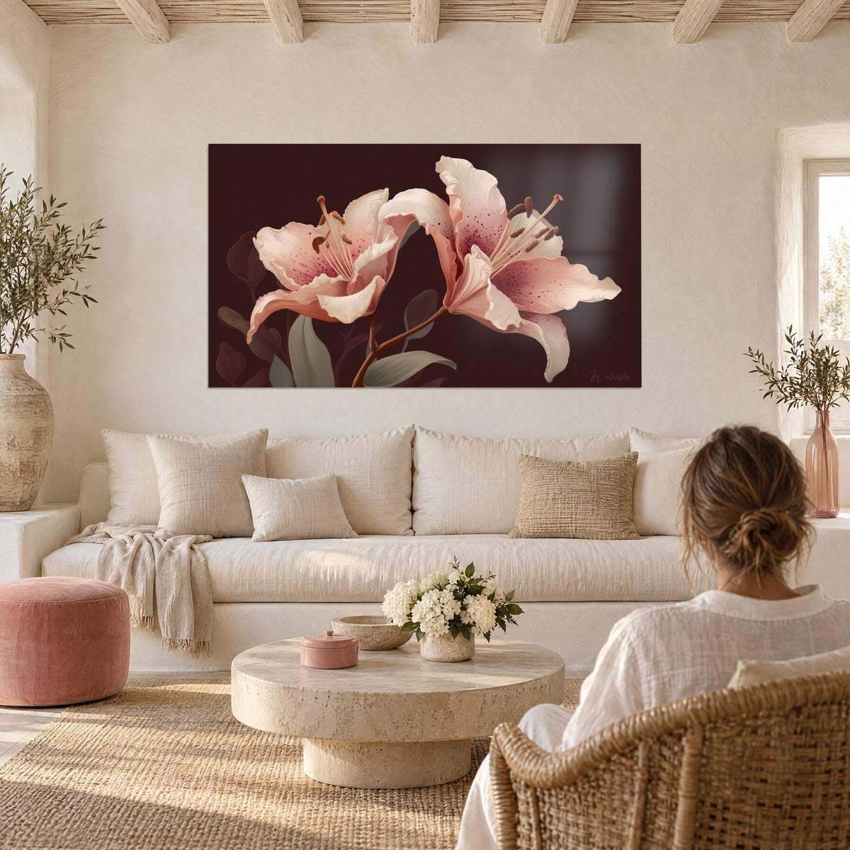 Quadro di petali di giglio rosa cipria punteggiati di cremisi su fondo marrone intenso, donna di spalle sopra un divano in un soggiorno luminoso