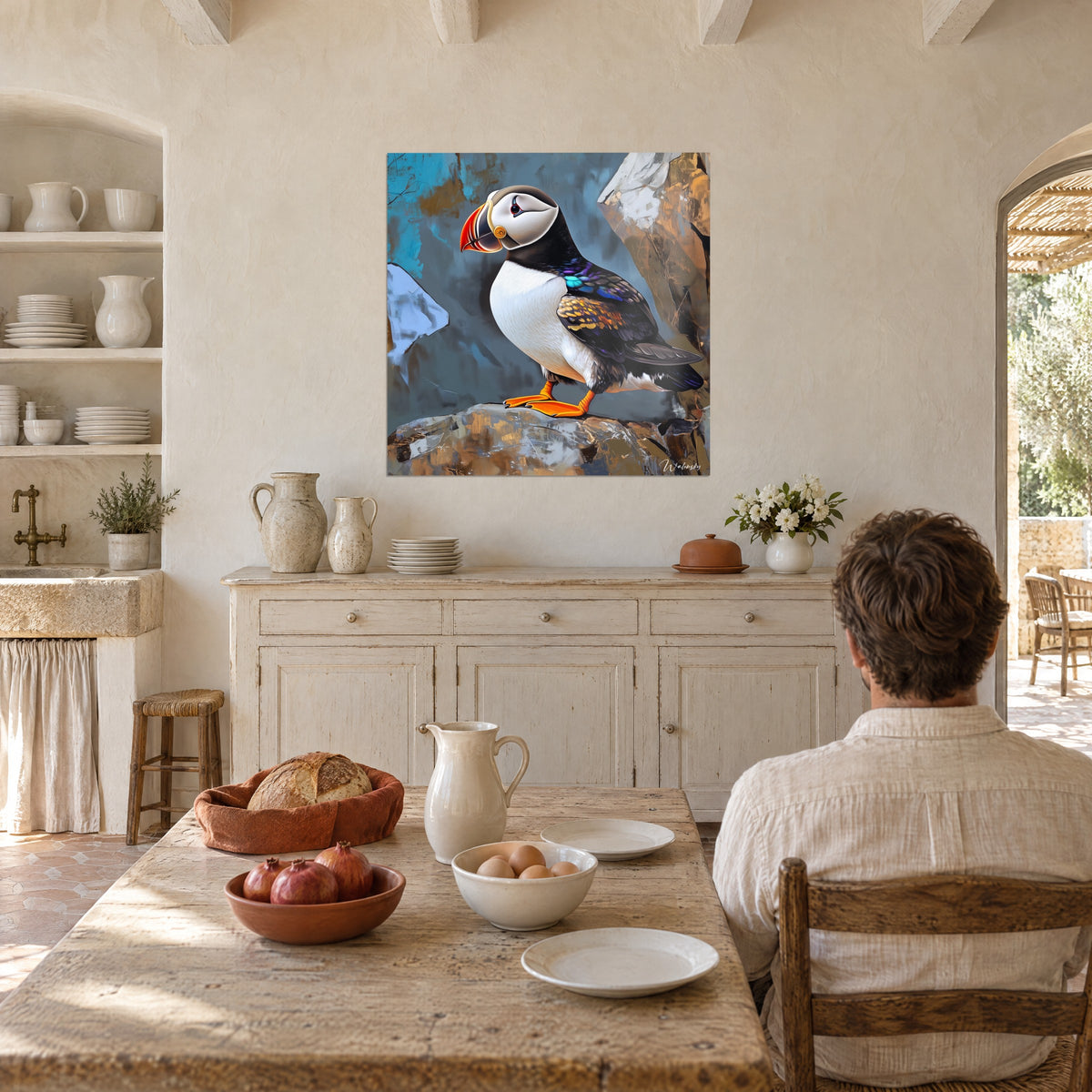 Quadro pulcinella di mare di profilo, petto avorio e ali blu-violetto, appeso accanto a un tavolo in legno di una masseria, di spalle