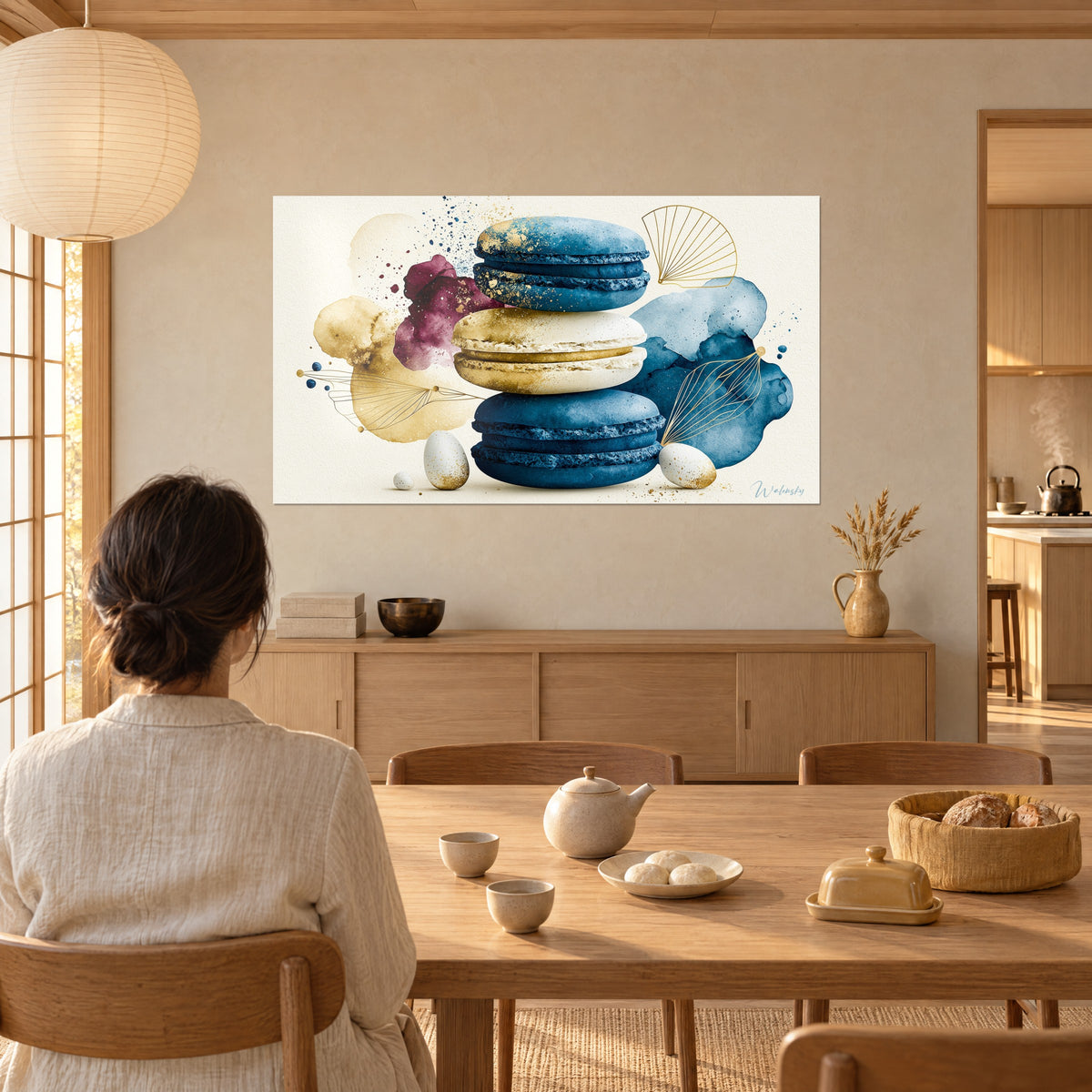 Gemälde mit französischem Gebäck in Kobaltblau und Gold, weiß gesprenkelte Eier, sitzende Frau von hinten, beige Wand und Fenster mit Lamellen