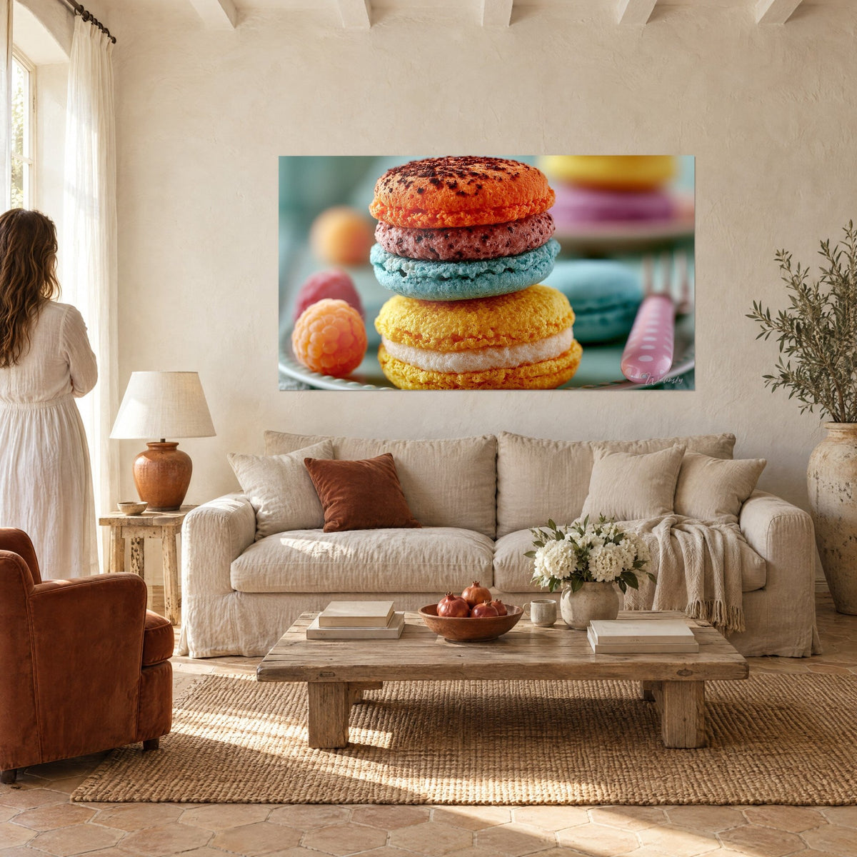 Tableau pile de macarons orange, bleu et jaune posée près d'une framboise, au-dessus d'un canapé dans un salon lumineux