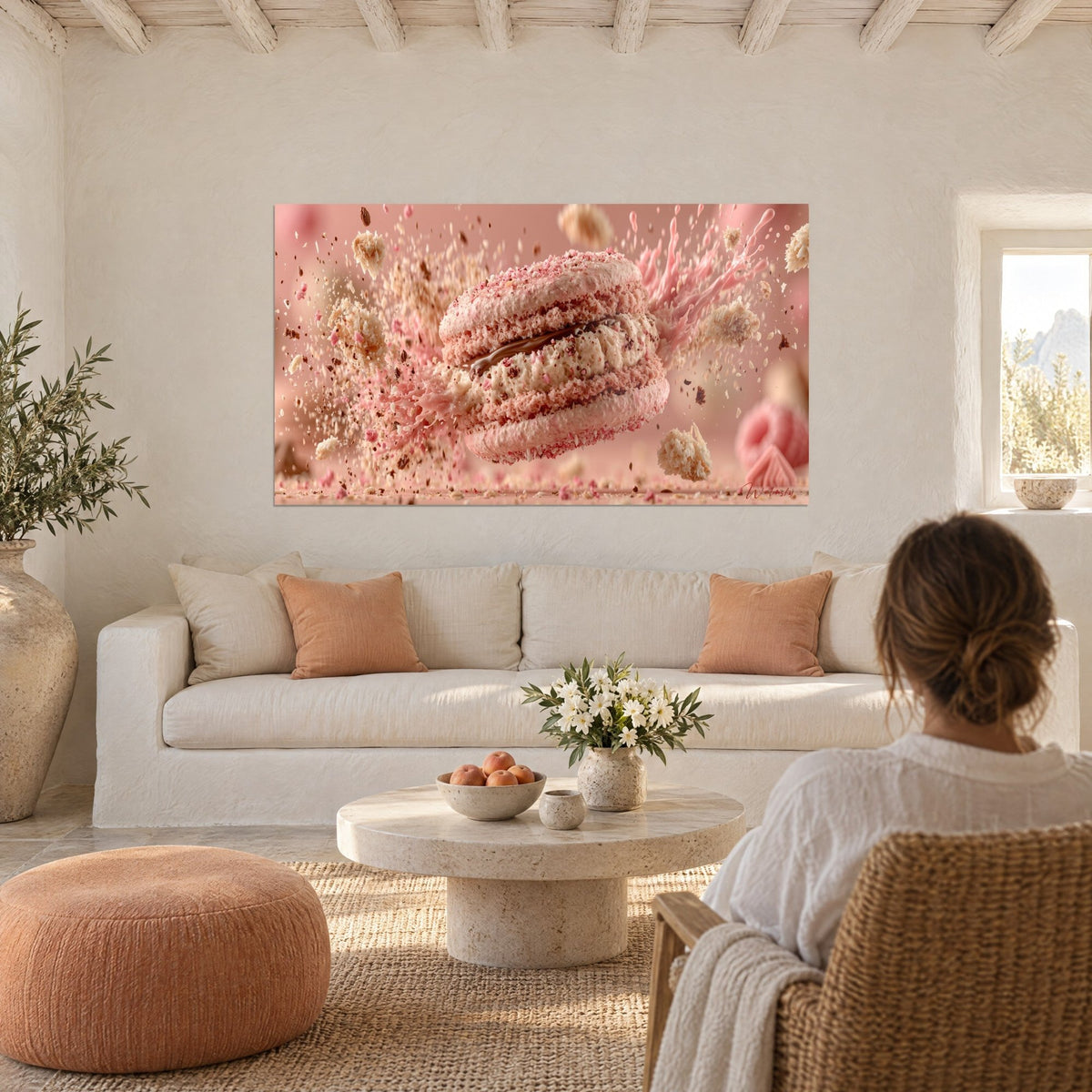 Tableau macaron rose explosant en miettes, coulée chocolat et crème ivoire, au-dessus d'un canapé dans un salon lumineux