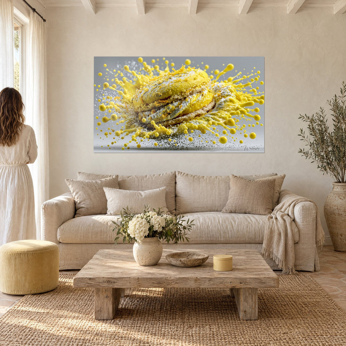 Tableau macaron citron éclaté en gouttelettes jaunes et grises, couple de dos, au-dessus d'un canapé dans un salon lumineux